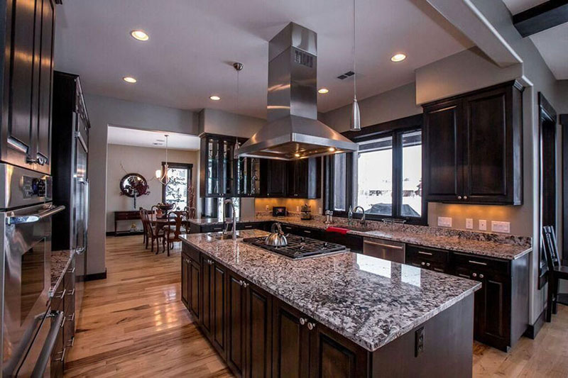 Kitchen With Dark Cabinets And White Wave Granite Countertops